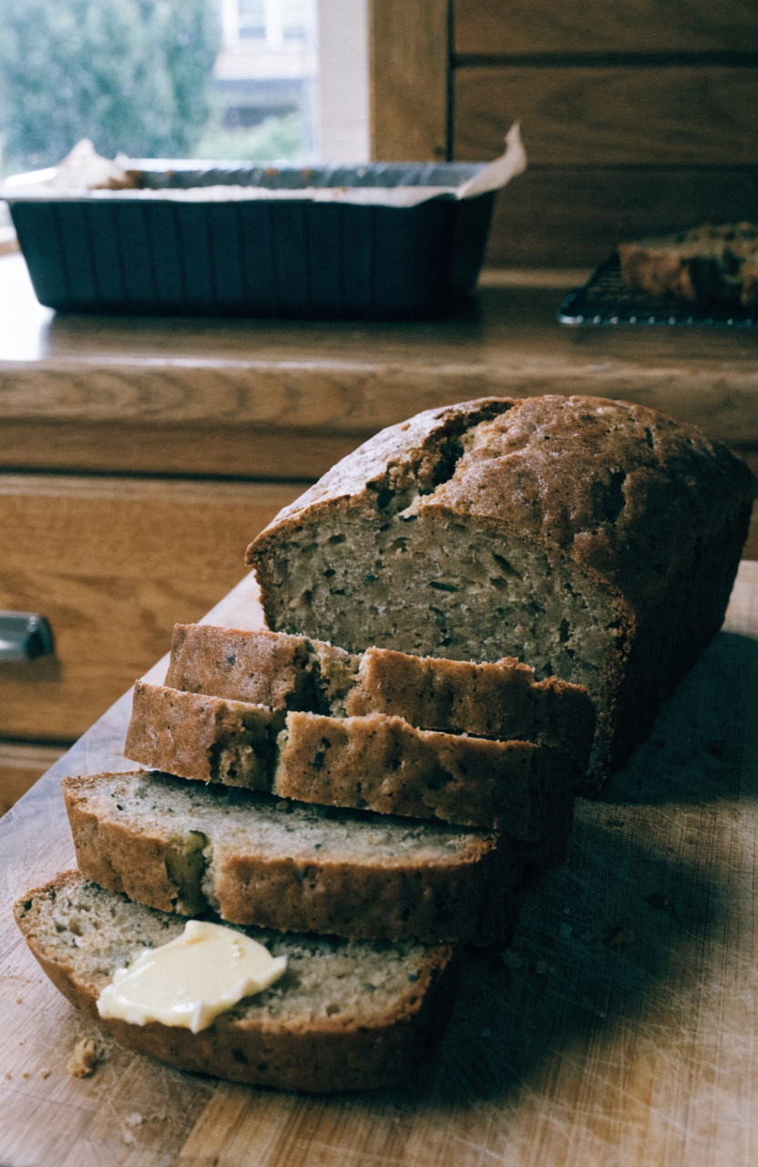 Sliced zucchini bread on a wooden board with a cooling rack
